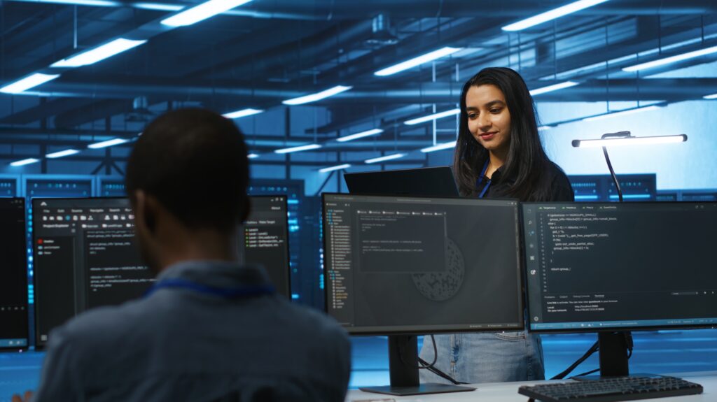 Cheerful supervisor in server room managing multiethnic team of technicians